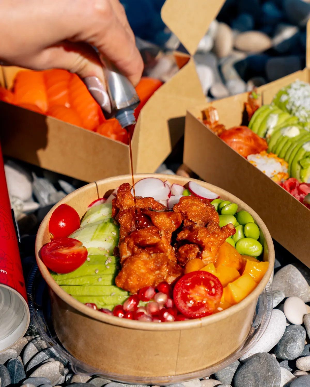 Poke bowl à emporter tenu sur la plage de galets