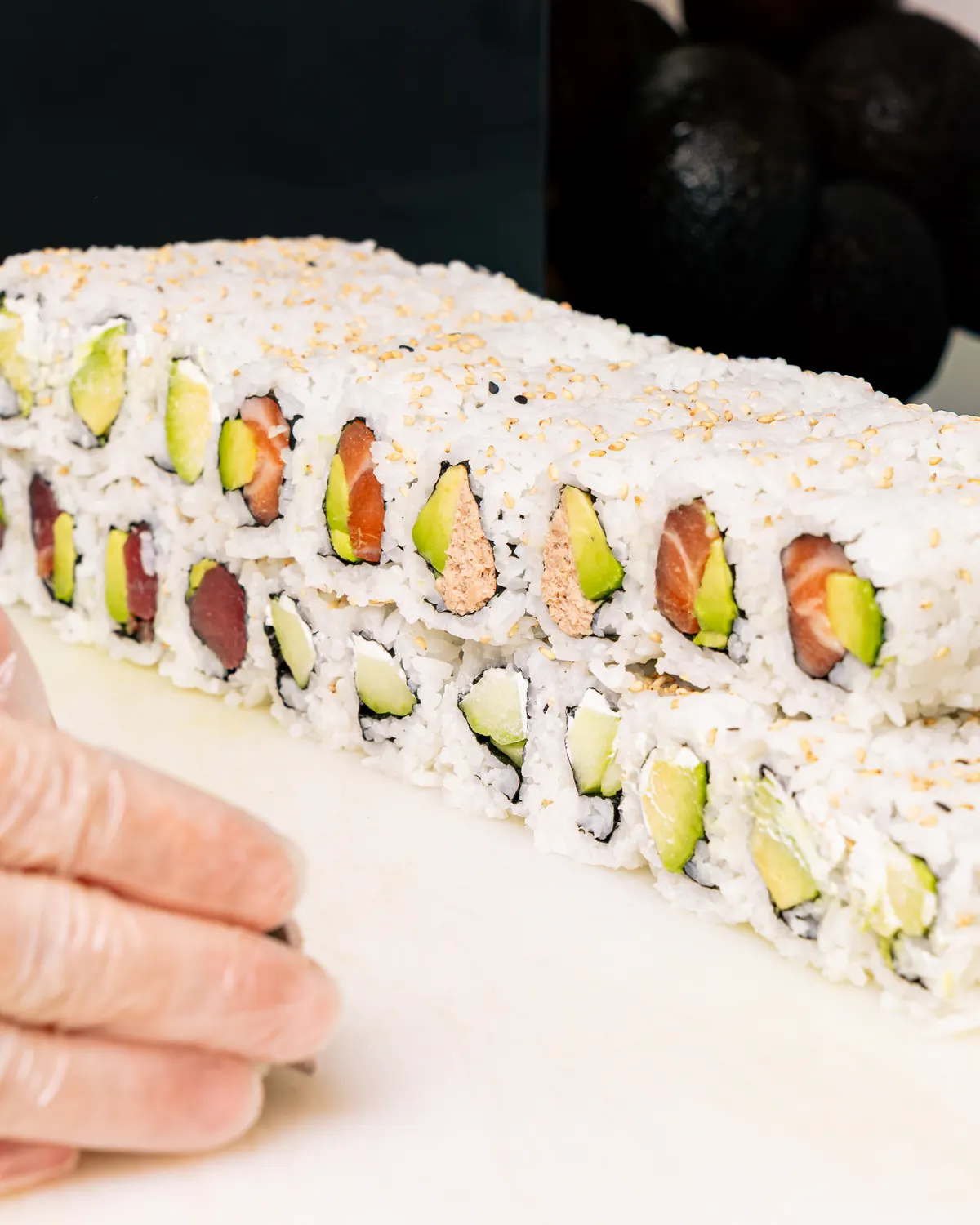 Des california rolls saumon, thon et avocat tranchés au couteau chez Mas Sushi